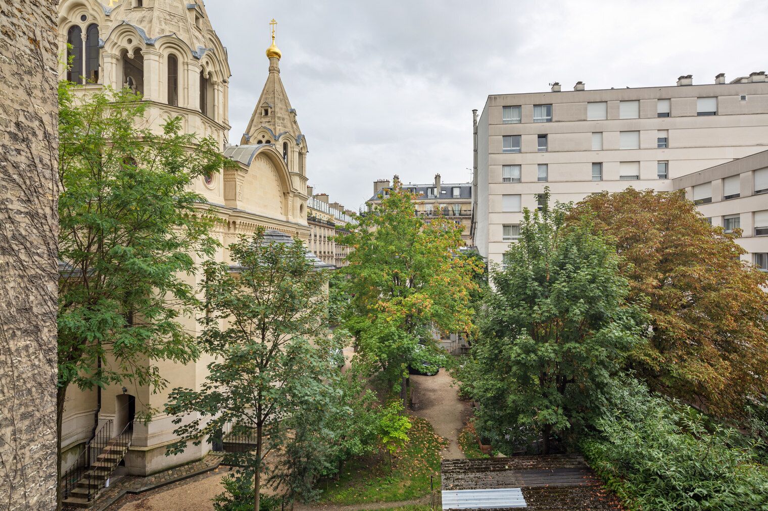 Un edificio storico dall'architettura elaborata, una chiesa con un campanile imponente e, sullo sfondo, un moderno palazzo condominiale.