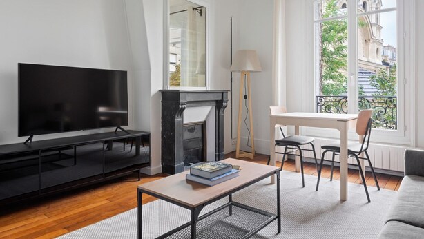 A modern living room with a flat-screen TV, a fireplace, a dining table with chairs, and a sofa. - Blueground | Arc de Triomphe, nr Parc Monceau (Paris)