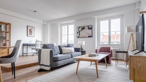 A modern living room with a grey sofa, a wooden coffee table, and a pink armchair. - Blueground | Montparnasse, furnished & equipped (Paris)