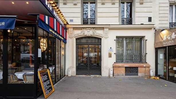 A building with a black awning, a signboard, and a bench in front. - Blueground | Montparnasse, furnished & equipped (Paris)