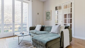 A modern living room with a grey sofa, a glass coffee table, and a view through large windows to the outside. - Blueground | Trocadero, elevator, nr Eiffel Tower (Paris)