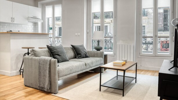A modern living room with a grey sofa, a coffee table, and a TV stand.