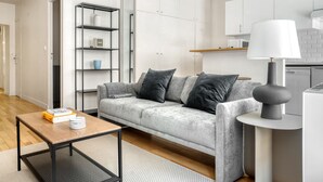 A modern living room with a grey sofa, a coffee table, and a bookshelf.