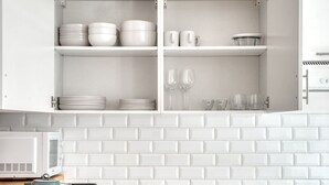 A kitchen with white cabinets, a microwave, and a tiled backsplash.