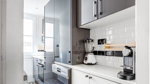 Une cuisine moderne équipée d’un mixeur encastré, d’une machine à café et d’une fenêtre laissant entrer la lumière naturelle.
