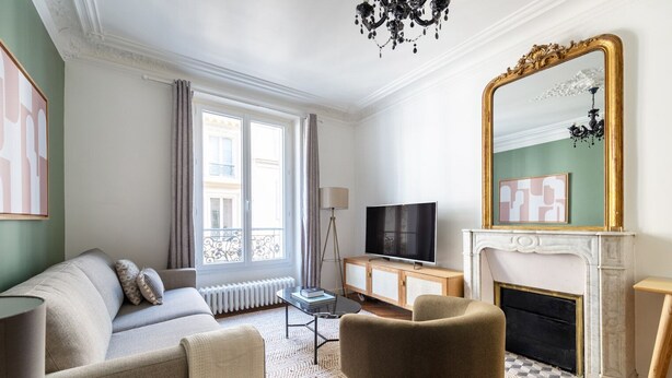 Un salon moderne comprenant un canapé, un fauteuil, une télévision, une cheminée et un grand miroir.