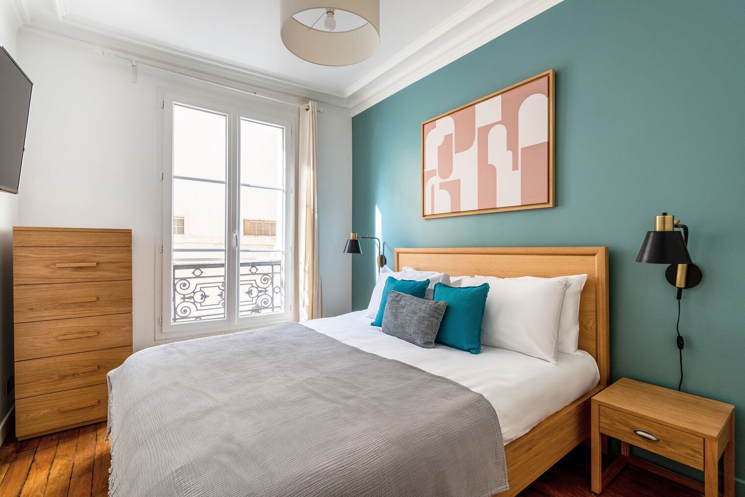 Quarto com cama, mesas de cabeceira, guarda-roupa e vista para a varanda.