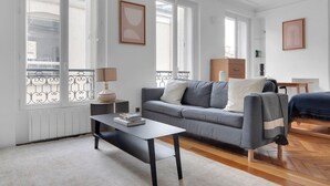 Ein modernes Wohnzimmer mit einem grauen Sofa, einem kleinen Couchtisch und einem Bücherregal.