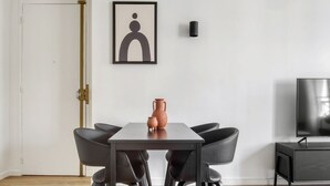 A dining area with a table, chairs, a vase, and a television. - Blueground | Saint Lazare, elevator, near opera (Paris)