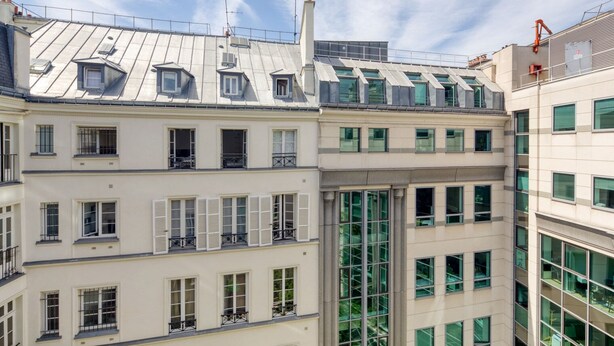 A multi-story building with a mix of residential and commercial spaces, featuring large windows, balconies, and a modern architectural design. - Blueground | Saint Lazare, elevator, near opera (Paris)