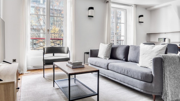 A modern living room with a grey sofa, a black chair, and a wooden coffee table.