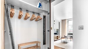 A modern, minimalist bathroom with wooden towel racks, a bench, and a shower area.
