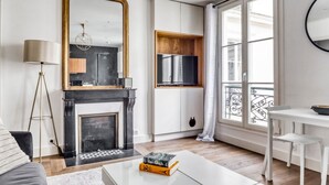 Un salon moderne avec une cheminée, un grand miroir et un téléviseur fixé sur un meuble en bois.