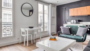 Un appartement moderne comprenant un coin repas, un canapé, une table basse et une cuisine en arrière-plan.