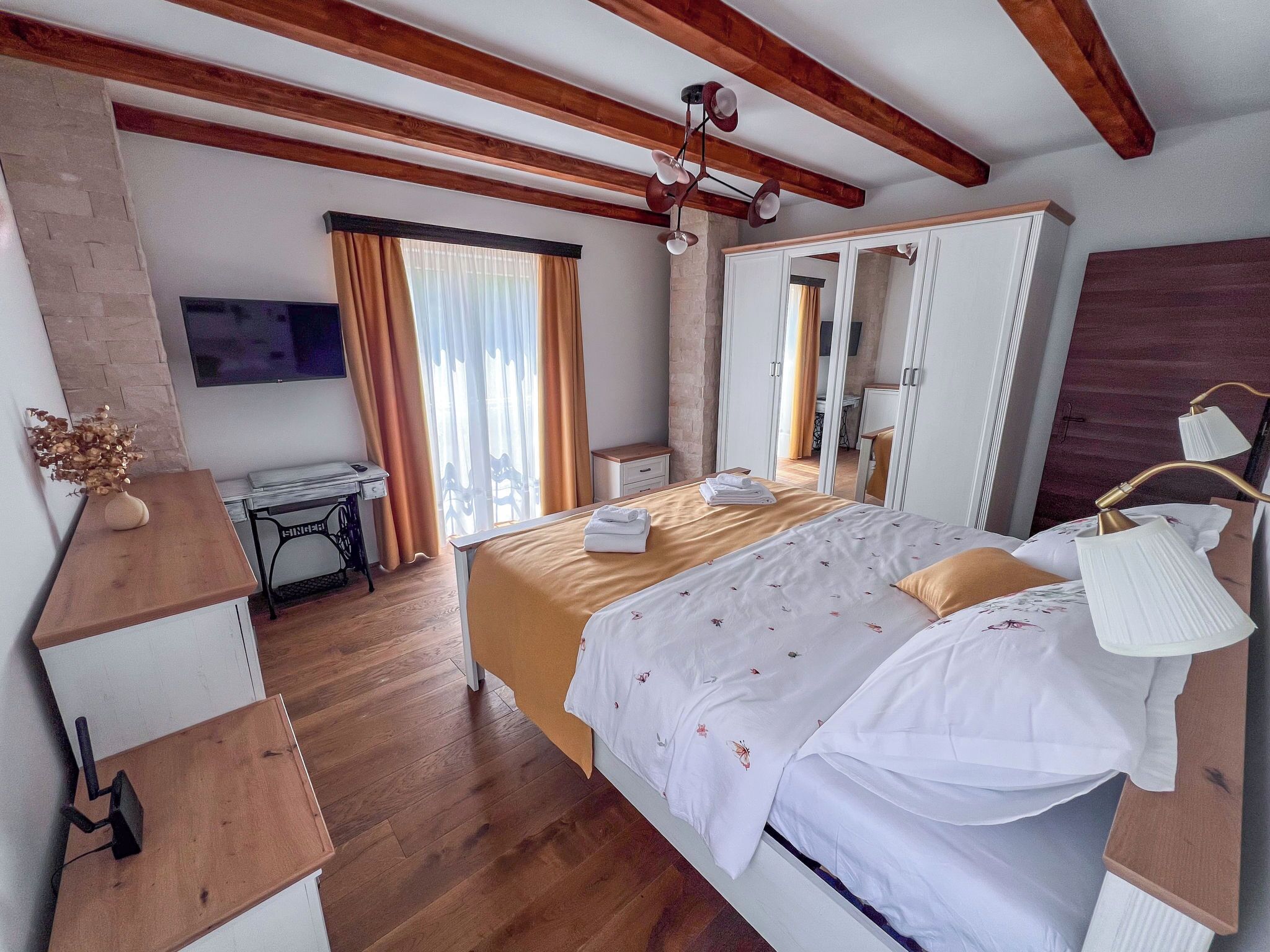 Ein Hotelzimmer mit Bett, Schreibtisch, Spiegel und Fernseher.