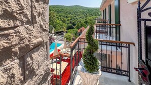 A hotel with a pool, outdoor seating, and a view of a green hillside.