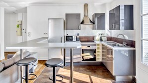 A modern kitchen with a central island, stainless steel appliances, and a large window. - Blueground | Bastille, elevator, nr Charonne (Paris)