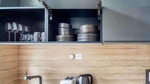 A compact kitchen with a sink, a toaster, a kettle, and a shelf with plates and glasses. - Blueground | Porte de Champerret, furnished (Paris)