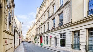 A narrow street lined with historic buildings, featuring a red door and a no parking sign. - Blueground | Invalides, concierge, a/c, nr museums (Paris)