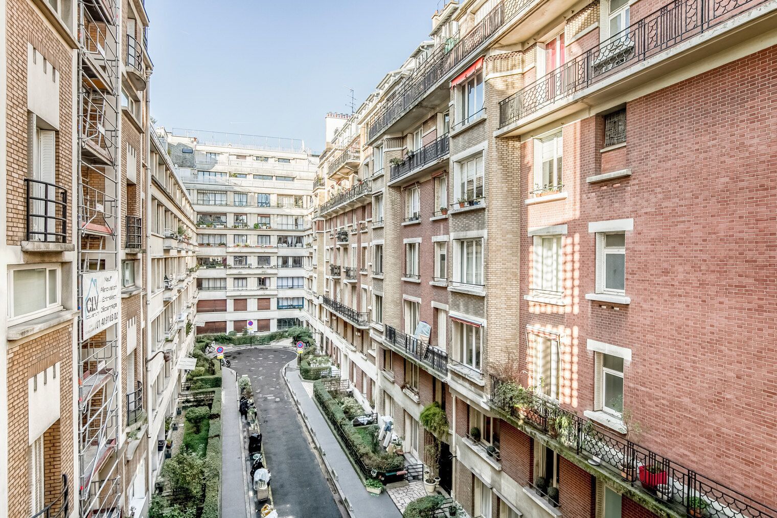 A multi-story residential building with balconies, a central courtyard, and a narrow street.