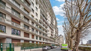 A multi-story residential building with balconies, a gated entrance, and a street with parked cars. - Blueground | Chardon Lagache, balcony & concierge (Paris)