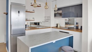 A modern kitchen with a stainless steel refrigerator, wooden countertops, a marble island, and pendant lights. - Blueground | Chardon Lagache, balcony & concierge (Paris)