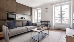 A modern living room with a sofa, coffee table, and dining area.