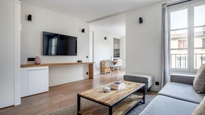 Una sala de estar moderna con una mesa de centro de madera, un sofá gris y un televisor montado en la pared.