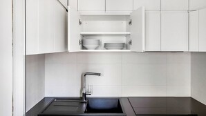 Una cocina moderna con armarios blancos, encimera negra y pileta integrada.