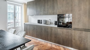 A modern kitchen with grey cabinets, a built-in oven, and a microwave. - Blueground | Vendome/Saint Honoré, furnished (Paris)