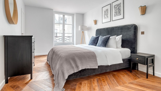 A bedroom with a bed, a wardrobe, a floor lamp, and artwork on the walls. - Blueground | Vendome/Saint Honoré, furnished (Paris)
