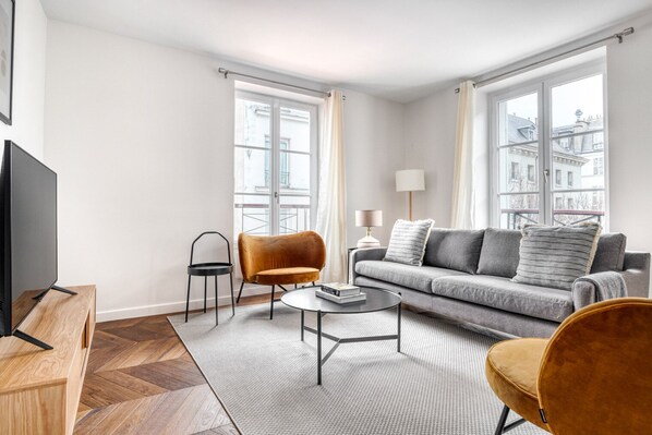 Relax in this stylish living room with a grey sofa, round coffee table, and flat-screen TV.