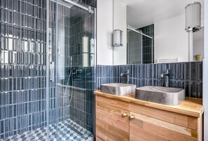 Enjoy a refreshing shower in the bathroom, featuring a geometric tile pattern and a spacious vanity with a large mirror.