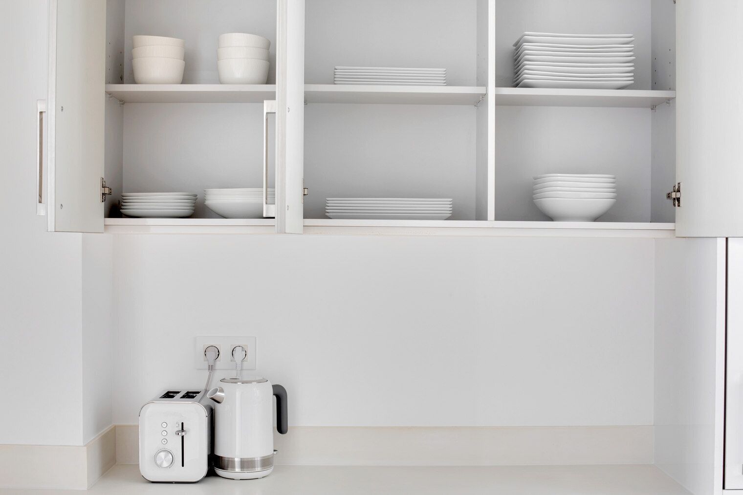 A kitchen with white cabinets, a toaster, and a kettle.