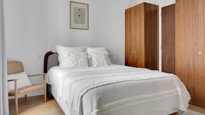 A bedroom with a bed, wooden wardrobe, and a framed picture on the wall.