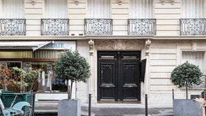 A building with a black double door, a sign reading "ERIE" above the entrance, and two potted trees in front.