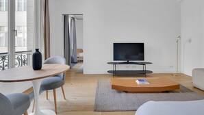 A modern living room with a flat-screen TV, a coffee table, and seating.