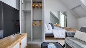 A modern bedroom with a loft bed, a wooden dresser, a TV, and a cozy seating area. - Blueground | George V, security, nr Champs Elysées (Paris)