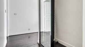 A hallway with white walls and dark wooden flooring. - Blueground | Champ de Mars, nr Eiffel Tower (Paris)