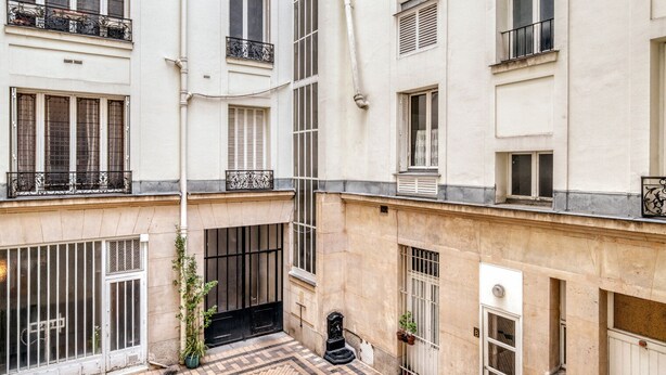 A multi-story building with balconies, a central courtyard, and a tiled floor. - Blueground | Batignolles, office & intercom (Paris)