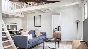 A modern living room with a blue sofa, a round coffee table, and a white staircase. - Blueground | Notre Dame de Lorette, nr opera (Paris)