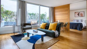 Et moderne hotelværelse med et stort vindue, en sofa med gule puder, et spiseområde og en seng.