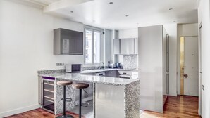 Eine moderne Küche mit Granit Arbeitsplatten, Edelstahlgeräten und einer integrierten Kochinsel mit Barhocker.