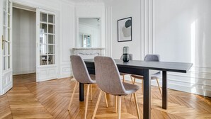 A dining area with a dark wooden table and two upholstered chairs with wooden legs. - Blueground | Levallois Perret, nr dining (Paris)