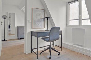 Work in comfort with a sleek desk and ergonomic chair, plus a large window for natural light and a unique sloped ceiling.