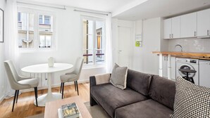 A modern, well-lit apartment with a dining area, sofa, and kitchenette. - Blueground | Montorgueil, intercom, nr Les Halles (Paris)