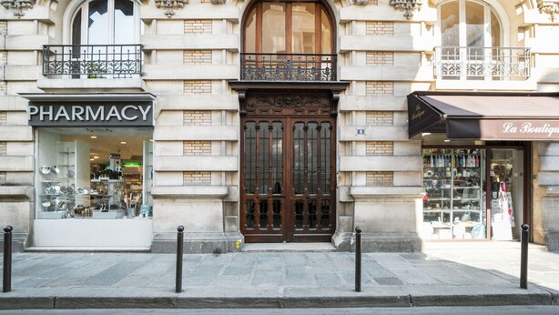 A building with a pharmacy on the left and a boutique on the right. - Blueground | Invalides, elev, nr historic museums (Paris)