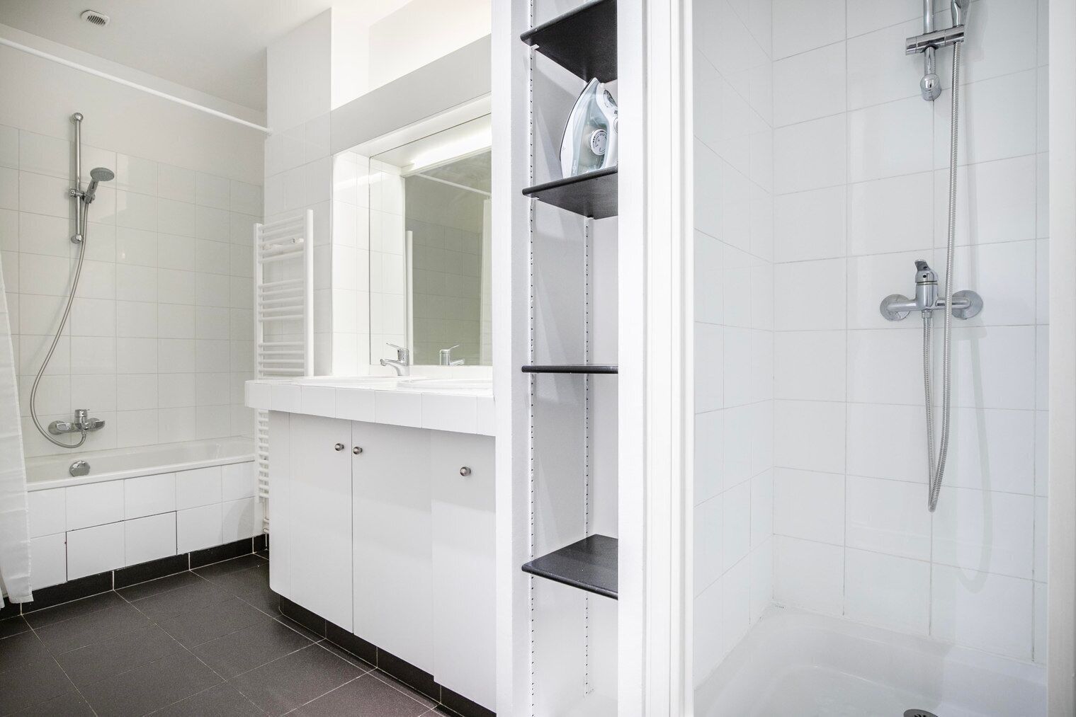 A modern bathroom with a walk-in shower, a vanity with a mirror, and a toilet.