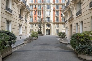 A courtyard with a central building featuring multiple balconies and a symmetrical facade. - Blueground | Pont de Neuilly, furnished, nr shops (Paris)