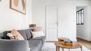 A living room with a grey sofa, a small wooden coffee table, and a door in the background. - Blueground | St Paul, nr Bastille & Le Marais (Paris)